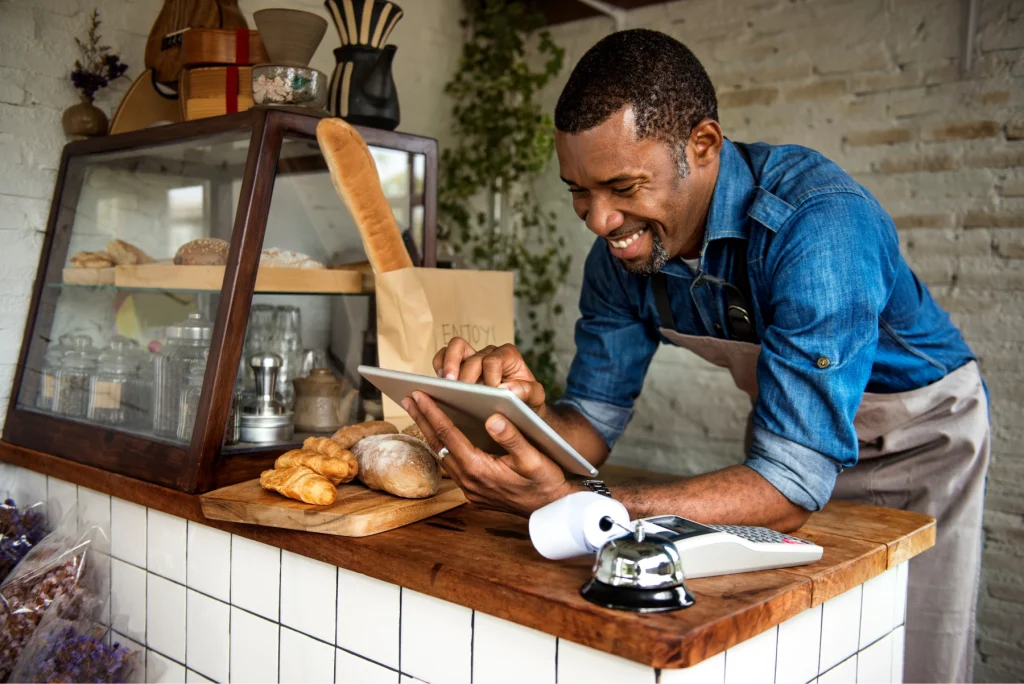 Local bakery owner smiling and reading a tablet